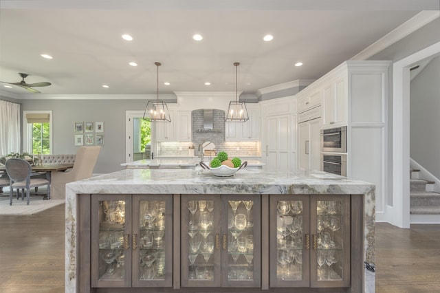 kitchen with a large island with sink, white cabinetry, and pendant lighting