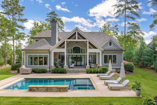 back of property with a swimming pool with hot tub, a lawn, and a patio area