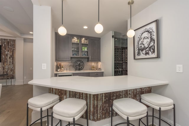 kitchen featuring pendant lighting, backsplash, a kitchen breakfast bar, and dark brown cabinetry