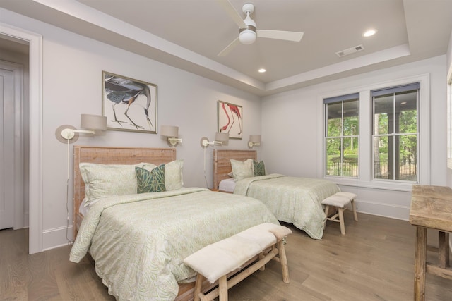 bedroom featuring hardwood / wood-style floors, ceiling fan, and a tray ceiling