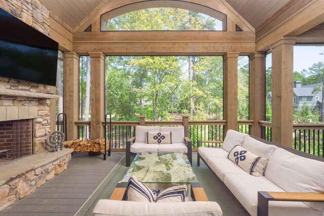 sunroom with lofted ceiling, wooden ceiling, and a stone fireplace