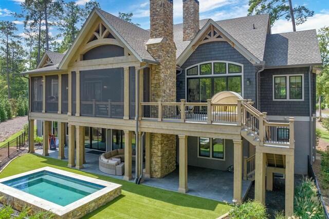 rear view of property with an outdoor living space, an in ground hot tub, a sunroom, and a patio area