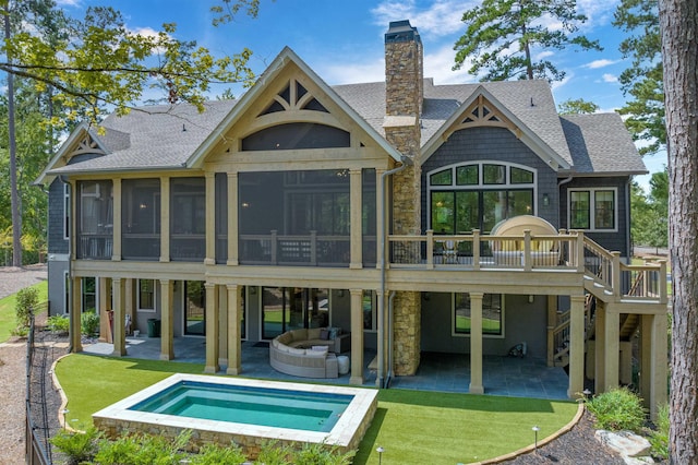 back of house with a patio, a lawn, outdoor lounge area, a hot tub, and a sunroom