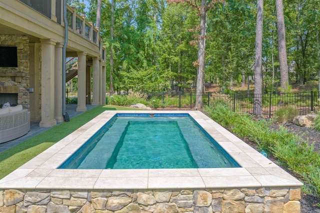 view of swimming pool featuring an outdoor stone fireplace and a patio area