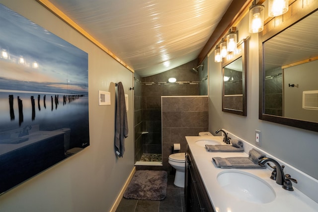 bathroom featuring a tile shower, lofted ceiling, vanity, toilet, and tile patterned floors