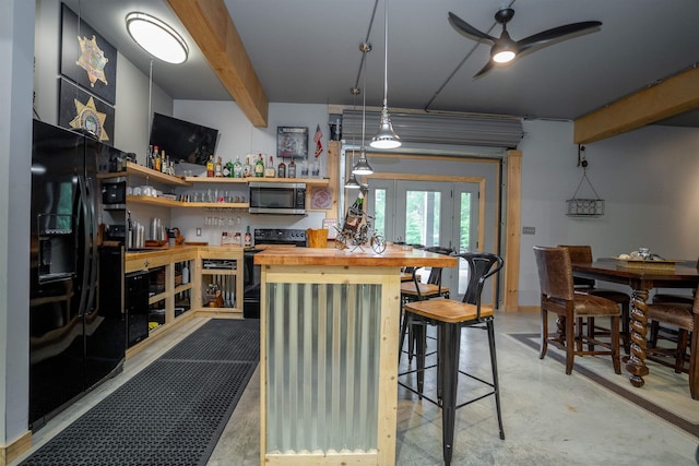 kitchen featuring decorative light fixtures, butcher block counters, beam ceiling, and black appliances