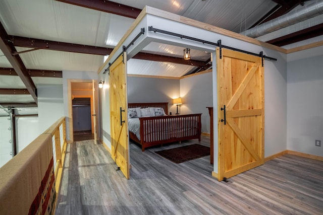 bedroom featuring dark hardwood / wood-style flooring, lofted ceiling with beams, and a barn door