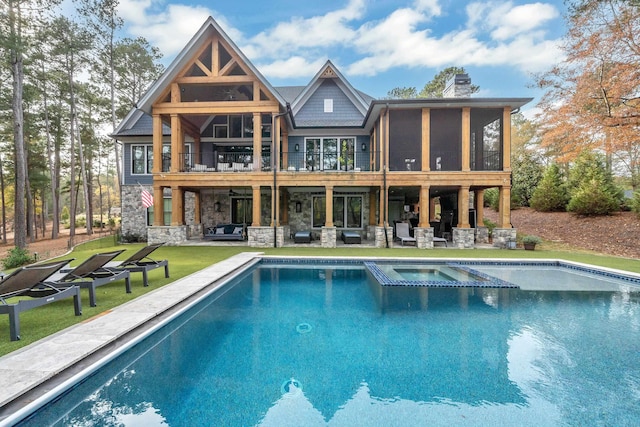 back of property with a balcony, a sunroom, a patio area, and a pool with hot tub