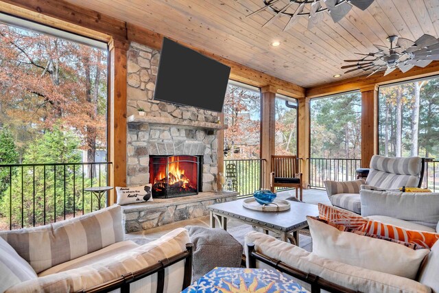 sunroom / solarium with ceiling fan, wooden ceiling, and a fireplace