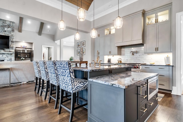 kitchen with stainless steel microwave, decorative light fixtures, gray cabinets, and a spacious island