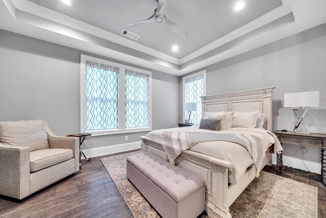 bedroom featuring dark hardwood / wood-style flooring, a raised ceiling, and ceiling fan