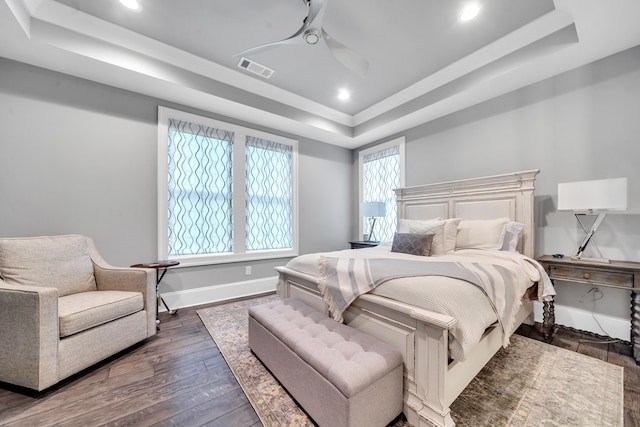 bedroom featuring dark hardwood / wood-style flooring, a raised ceiling, and ceiling fan