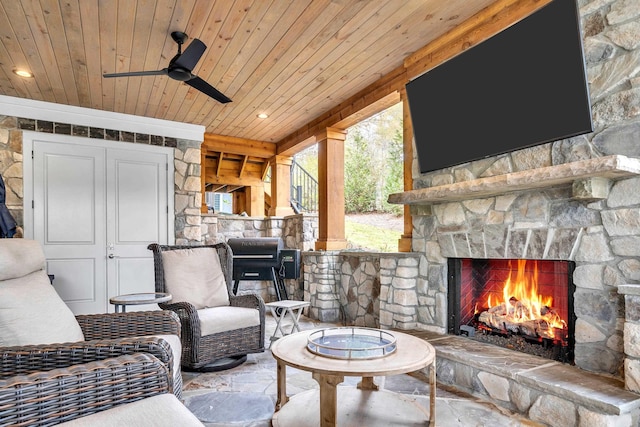 living room with ceiling fan, wood ceiling, and an outdoor stone fireplace