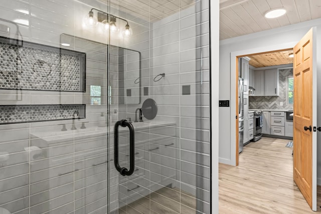 full bath featuring decorative backsplash, a shower stall, wood finished floors, and vanity
