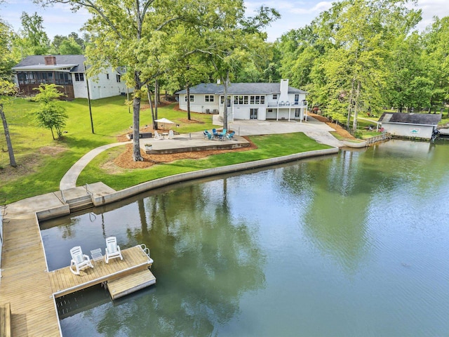 view of dock featuring a lawn, a deck with water view, and a patio area