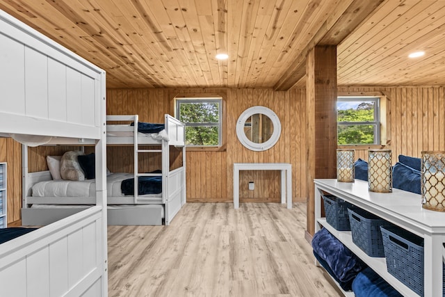 bedroom with wooden walls, multiple windows, wood ceiling, and wood finished floors