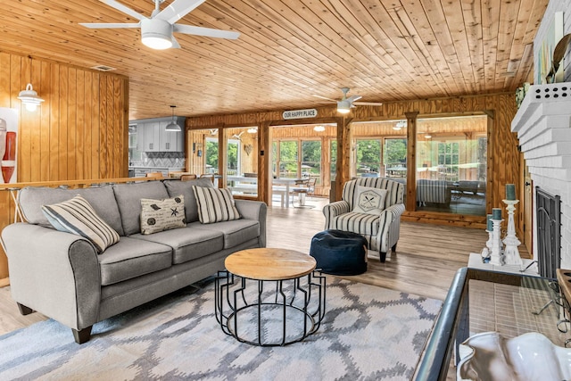 living room with wooden walls, wood ceiling, a ceiling fan, and wood finished floors