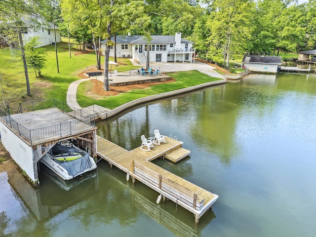 view of dock with a yard, a deck with water view, and a patio area