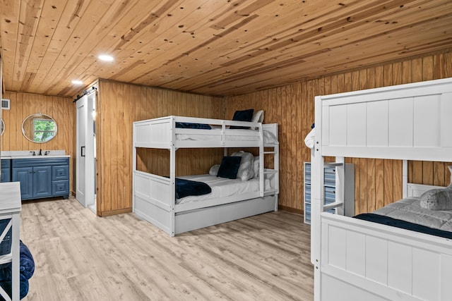 bedroom with a sink, wood ceiling, light wood-type flooring, and wood walls