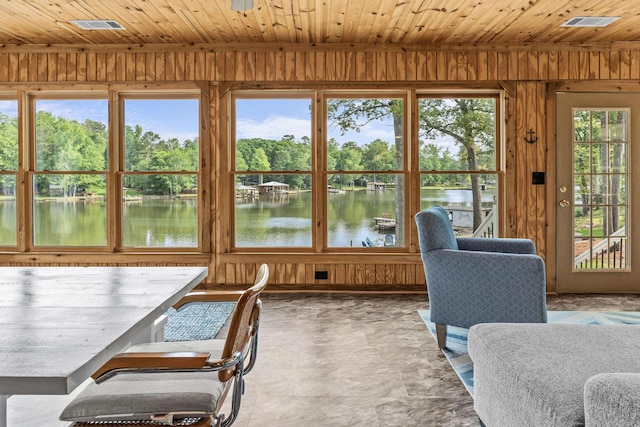 sunroom / solarium featuring a water view, wood walls, wood ceiling, and visible vents