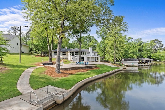 exterior space featuring a lawn, a water view, and a patio area