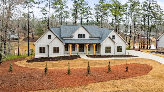 1050 Carnoustie Dr, Greensboro, GA 30642 - modern farmhouse style home with a shingled roof, covered porch, board and batten siding, and view of scattered trees