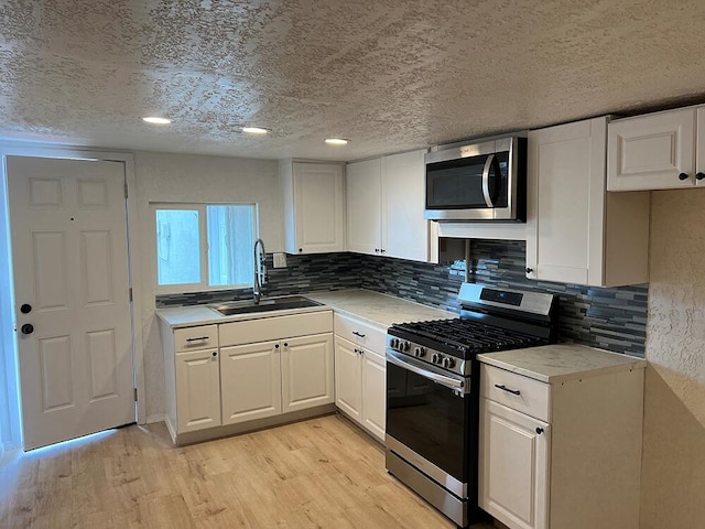 kitchen featuring white cabinetry, sink, appliances with stainless steel finishes, and light wood-type flooring