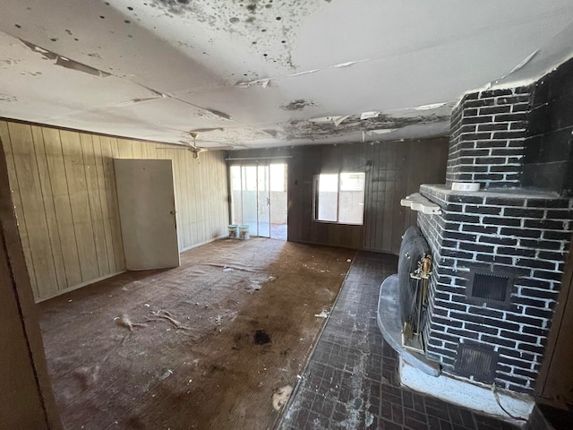 interior space featuring a fireplace, wood walls, brick wall, and a wood stove