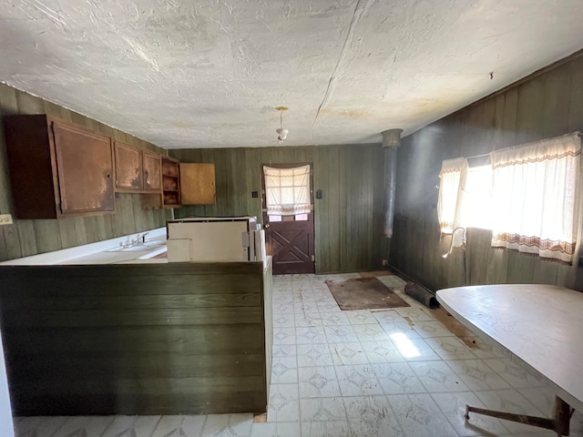 kitchen with light tile floors, wooden walls, and kitchen peninsula