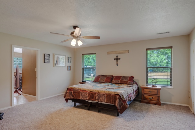 carpeted bedroom with ceiling fan and a textured ceiling