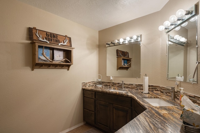 bathroom featuring a textured ceiling and dual bowl vanity