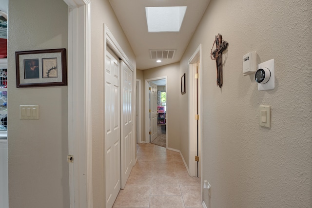 hall featuring light tile flooring and a skylight