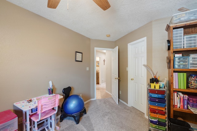 recreation room with ceiling fan, a textured ceiling, and light carpet