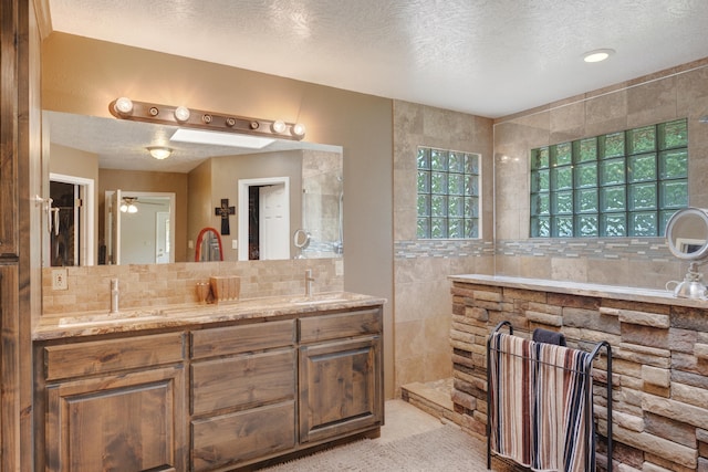 bathroom featuring tile walls, dual bowl vanity, and a textured ceiling