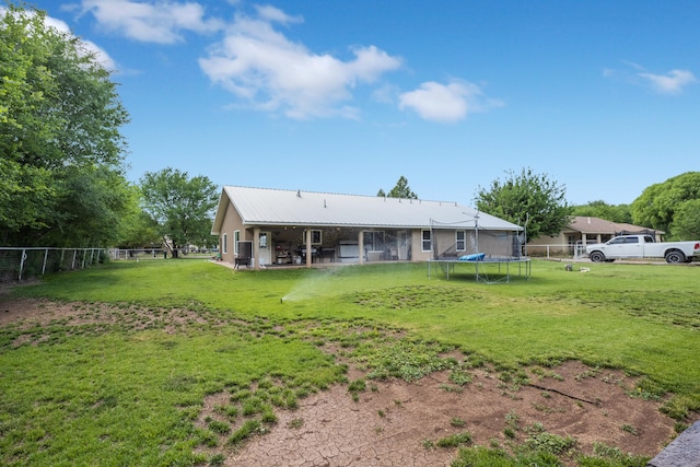 rear view of property with a trampoline, a lawn, and a patio area