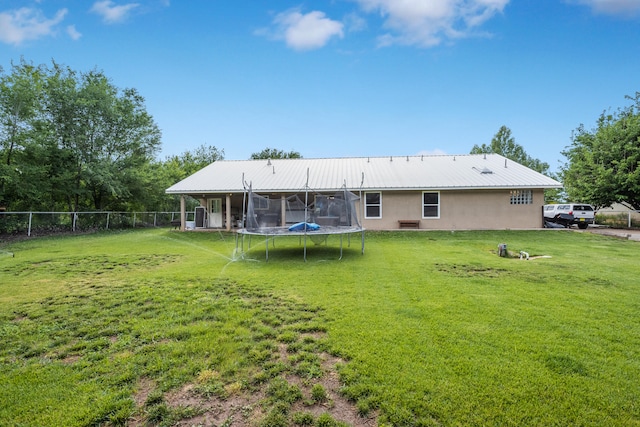 rear view of house with a trampoline and a yard