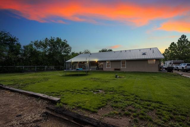 exterior space featuring a trampoline and a lawn