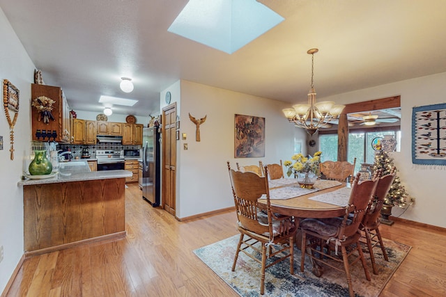 dining area featuring a skylight, light hardwood / wood-style flooring, sink, and ceiling fan with notable chandelier