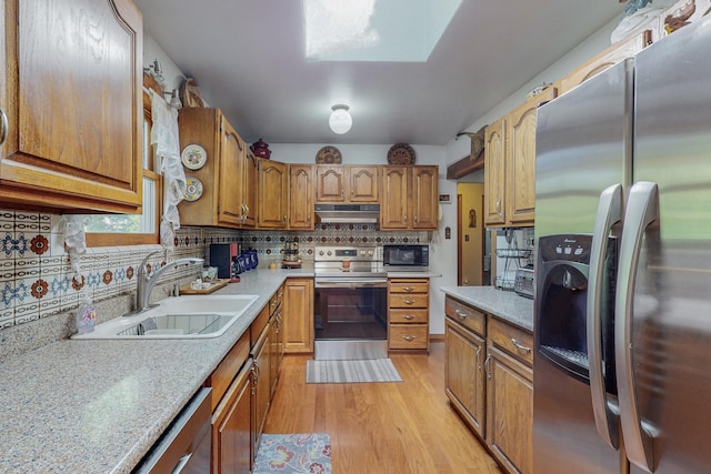 kitchen featuring backsplash, appliances with stainless steel finishes, light wood-type flooring, and sink