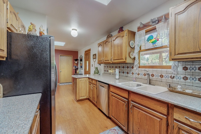 kitchen with backsplash, dishwasher, sink, and light wood-type flooring