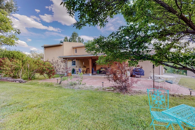 back of property featuring a lawn and a patio