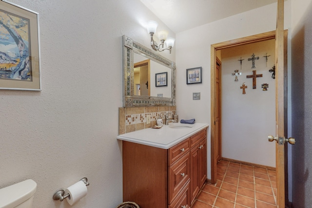 bathroom with backsplash, toilet, tile floors, and vanity with extensive cabinet space