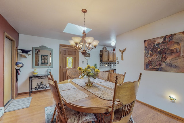 dining space featuring light hardwood / wood-style floors, a skylight, a chandelier, and baseboard heating