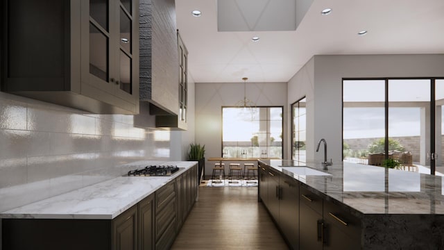 kitchen with dark brown cabinetry, sink, light stone counters, tasteful backsplash, and stainless steel gas stovetop