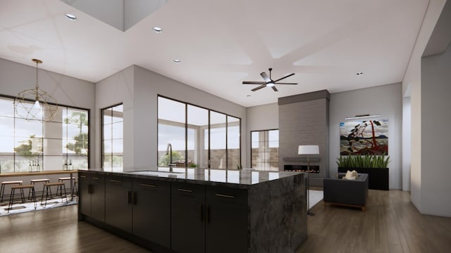 kitchen featuring dark hardwood / wood-style floors, a fireplace, sink, dark stone countertops, and a center island