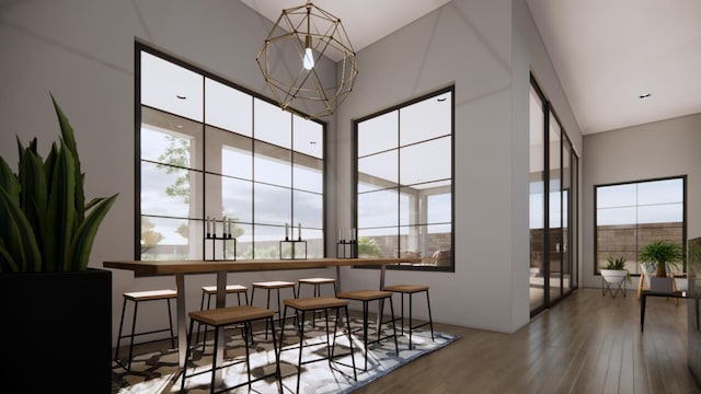 dining space with a high ceiling, wood-type flooring, and an inviting chandelier