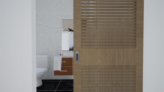 bathroom with tile walls, tile patterned flooring, and toilet