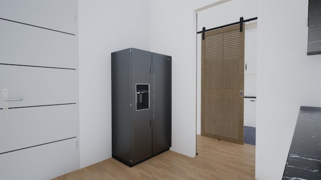 kitchen featuring black fridge, a barn door, and light wood-type flooring