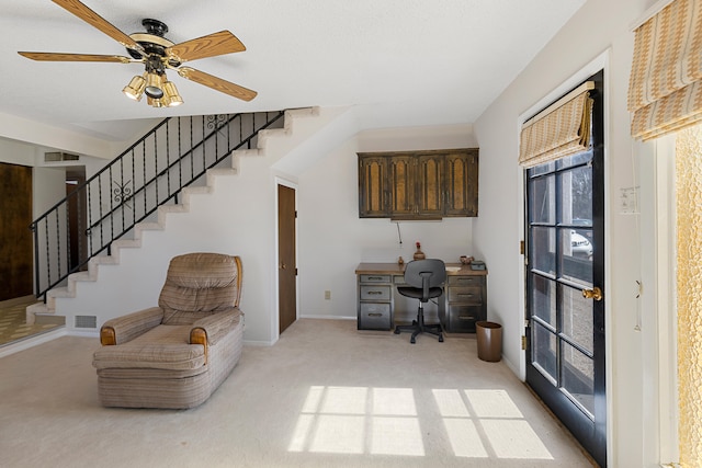 carpeted home office featuring ceiling fan and built in desk