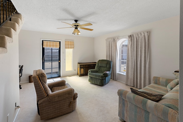 carpeted living room featuring ceiling fan and a textured ceiling